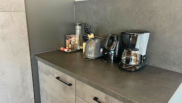 A kitchen counter with a coffee maker, toaster, and a box of coffee creamer.