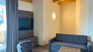 Una sala de estar moderna con un sofá gris, una mesa de centro de madera y un televisor montado en la pared.