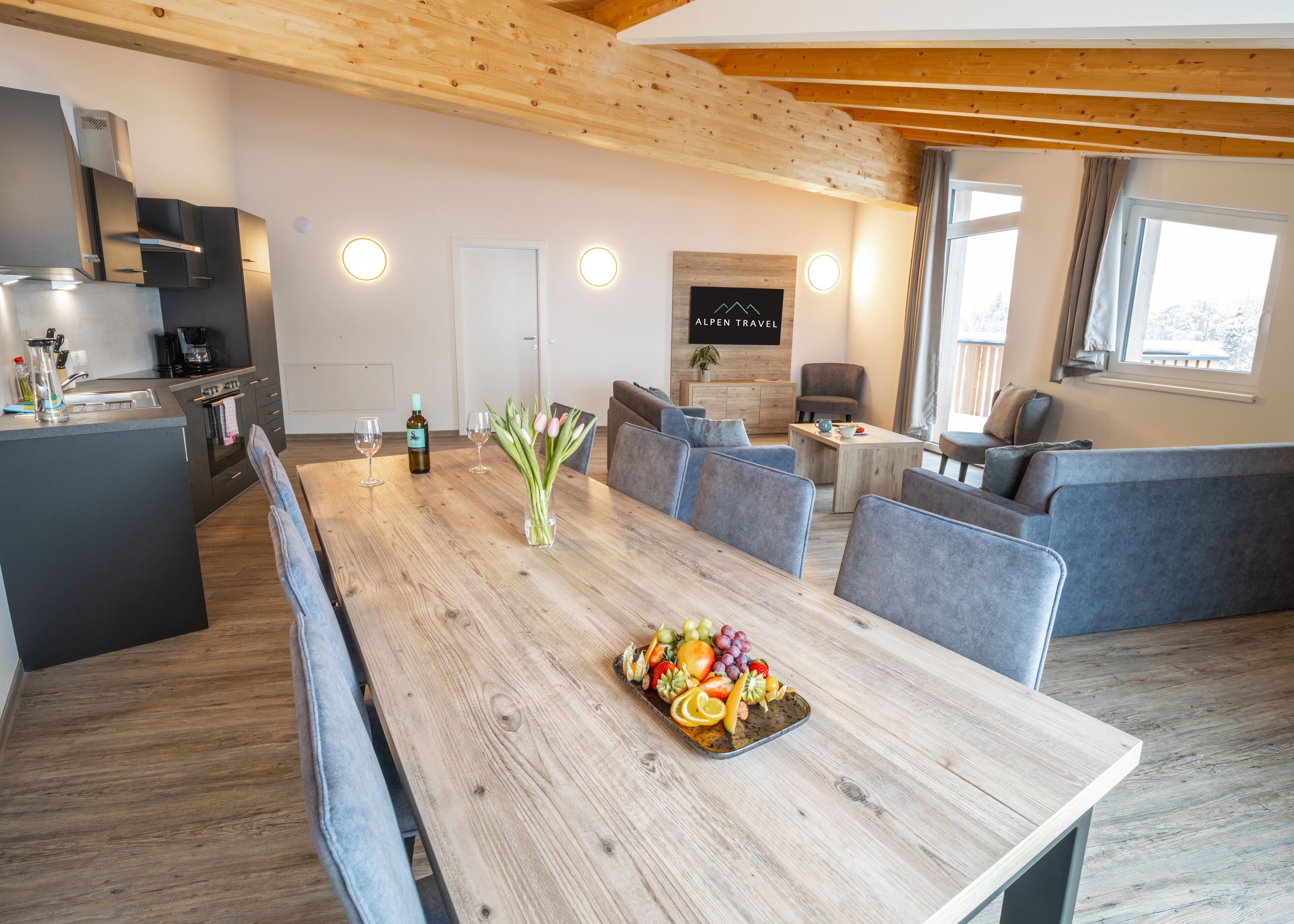 A modern kitchen with a built-in oven and a dining area with a wooden table set for a meal.
