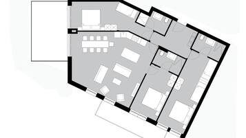 Een plattegrond van een hotel met meerdere kamers, een centraal zitgedeelte en een keuken.