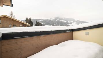 A wooden building with a snow-covered roof and a view of snow-covered mountains in the background.