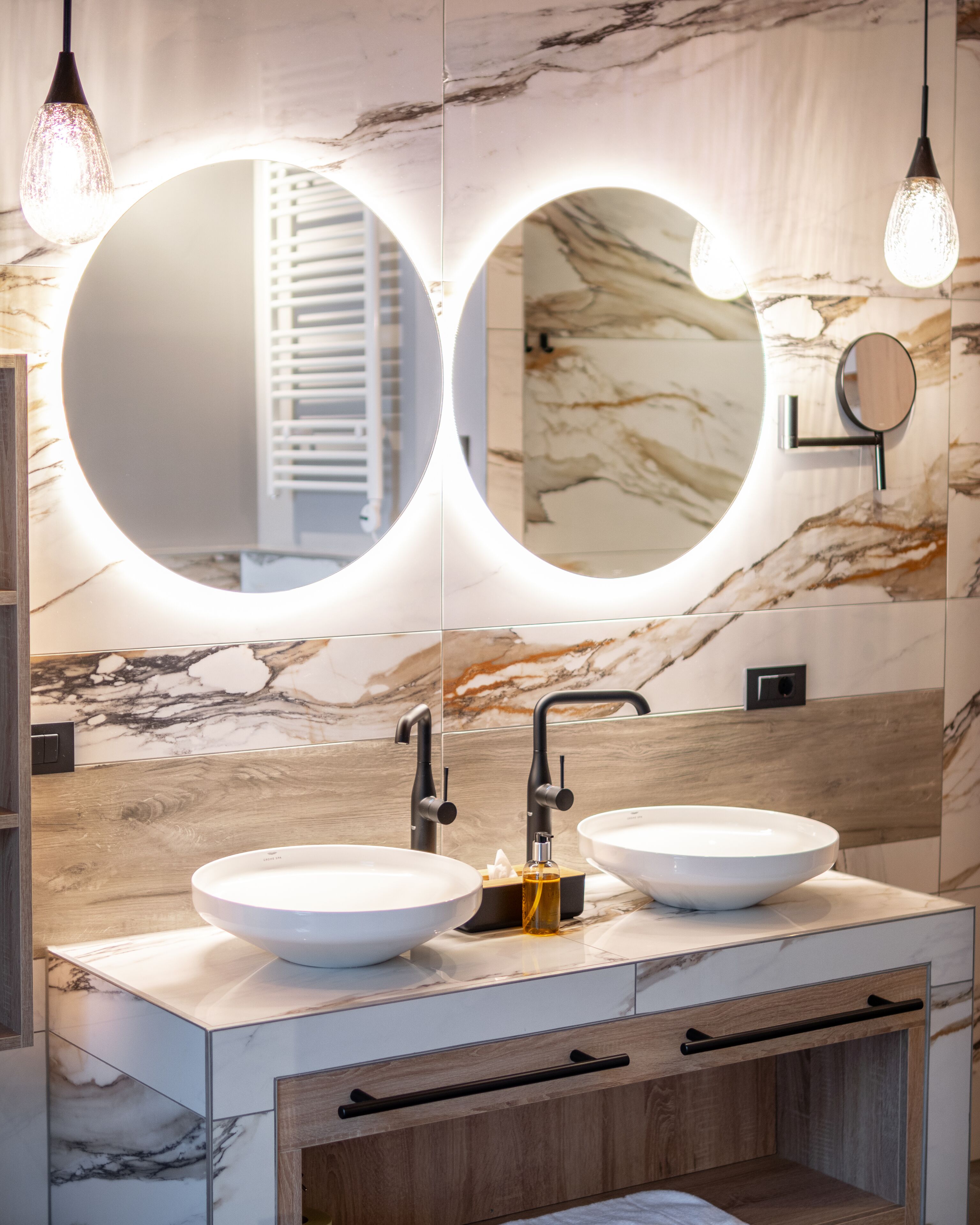A bathroom with two sinks, a large mirror, and a wooden vanity.