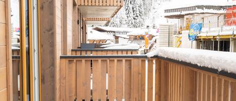 A wooden building with a balcony and a view of snow-covered trees.