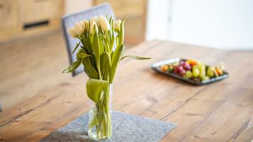 Une table en bois sur laquelle est posé un vase de fleurs blanches et une assiette de fruits.