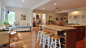 A spacious kitchen with a central island, bar stools, and a dining area with wooden chairs and a bench.