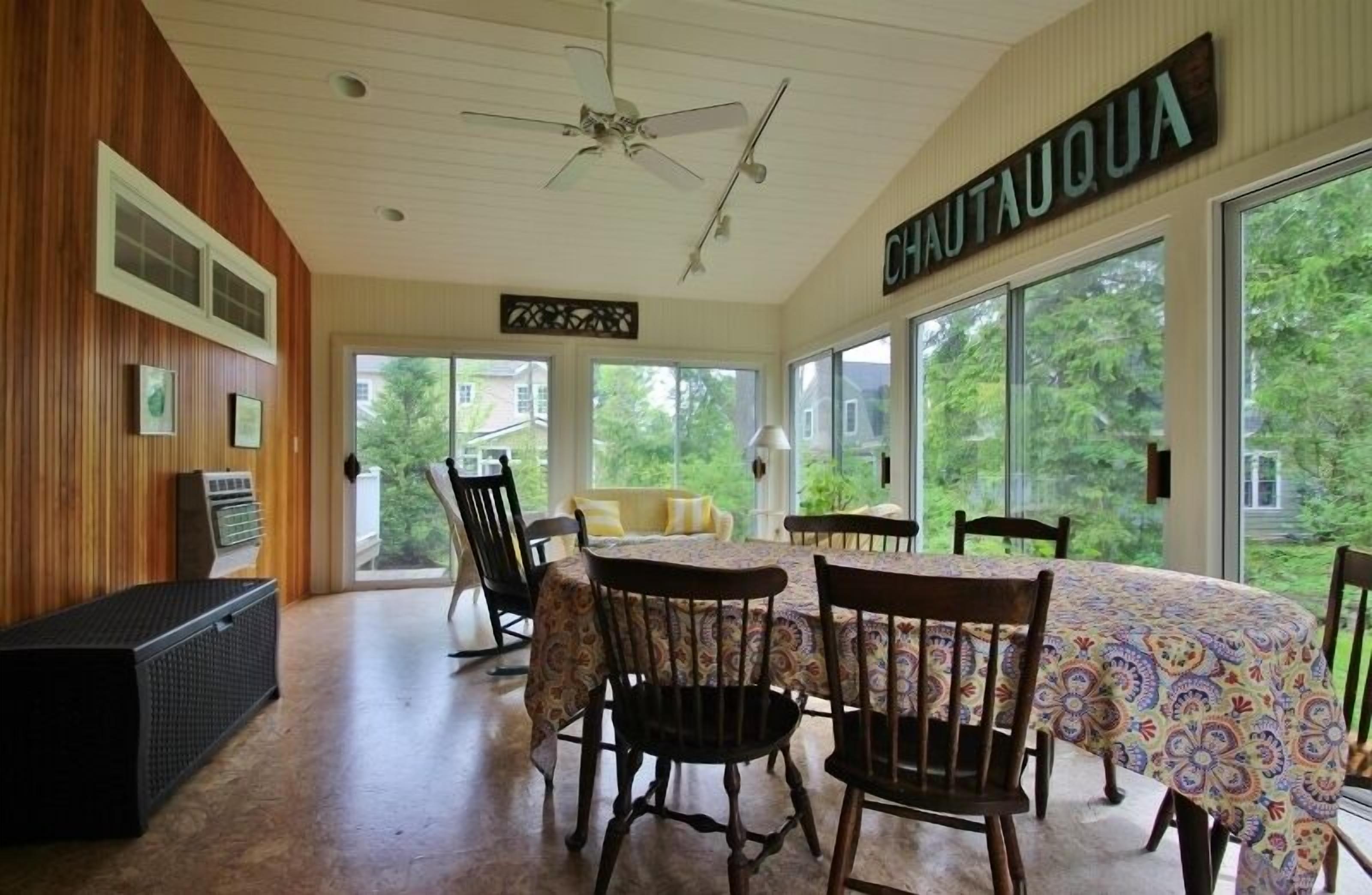 A dining area with a round table, chairs, and a ceiling fan.