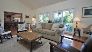 A spacious living room with a large sofa, a wooden coffee table, and a dining area with chairs.