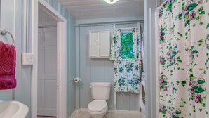 Une salle de bain équipée de toilettes, d’un lavabo et d’un rideau de douche orné d’un motif floral.