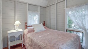 Une chambre à coucher avec un lit, une table de chevet, une lampe et une fenêtre avec des rideaux.