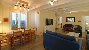 Un salon spacieux comprenant un coin repas, un téléviseur et un ventilateur de plafond.