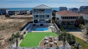 A multi-story building with a pool and outdoor seating area. - Discover Oak Island Nest Egg: a spacious 5-bedroom retreat with ocean views and private pool. (Oak Island)
