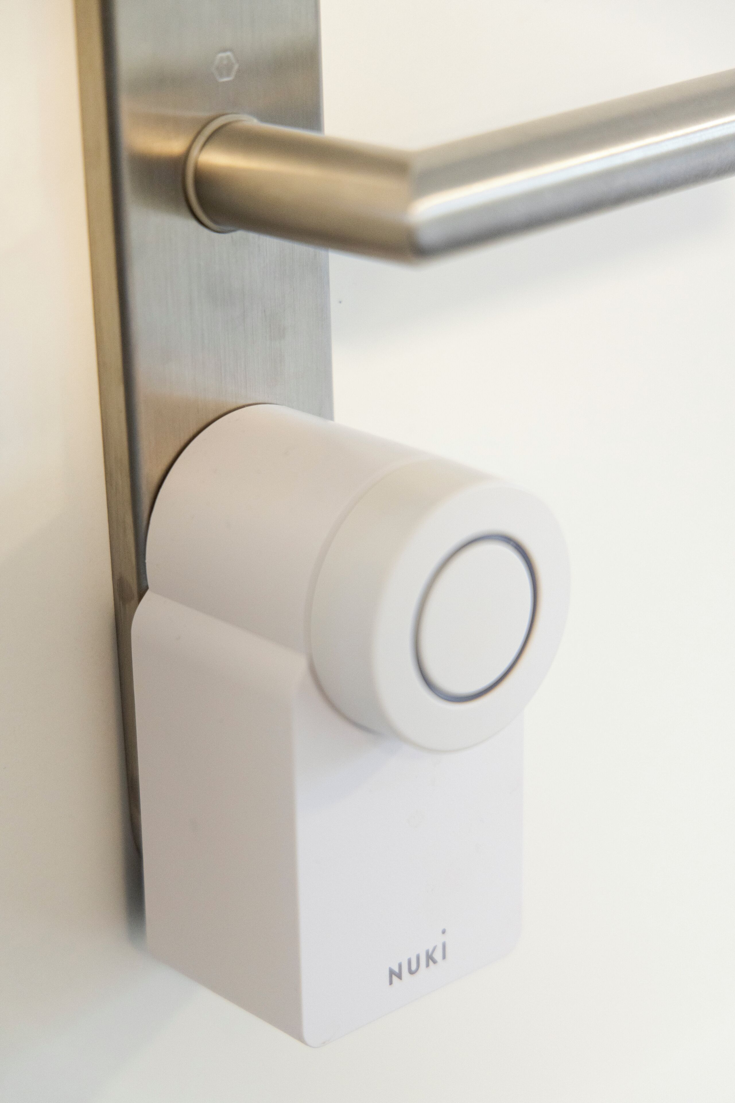 A modern door handle and a white, cylindrical object with the brand name "NUKI" on it.