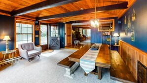 Een ruime kamer met een houten plafond, een grote eettafel en een gezellige zithoek.