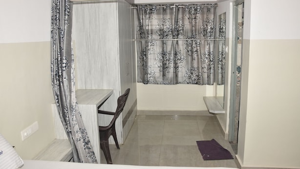 Una habitación pequeña y funcional con una cama, un escritorio y una silla. Cuenta con zona de ducha y cortina.