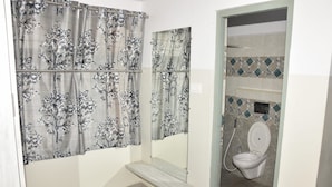 Un baño con inodoro, ducha y espejo.
