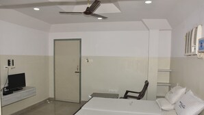 Una habitación de hotel con una cama, televisor, silla, escritorio y una puerta.