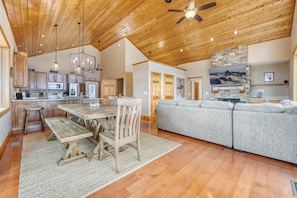A spacious kitchen with wooden cabinets, a dining table with chairs, and a stone fireplace.