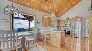 Een ruime keuken met houten kastjes, een centraal eiland en roestvrijstalen apparatuur.