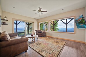A spacious living room with large windows, a ceiling fan, and a view of the outdoors.