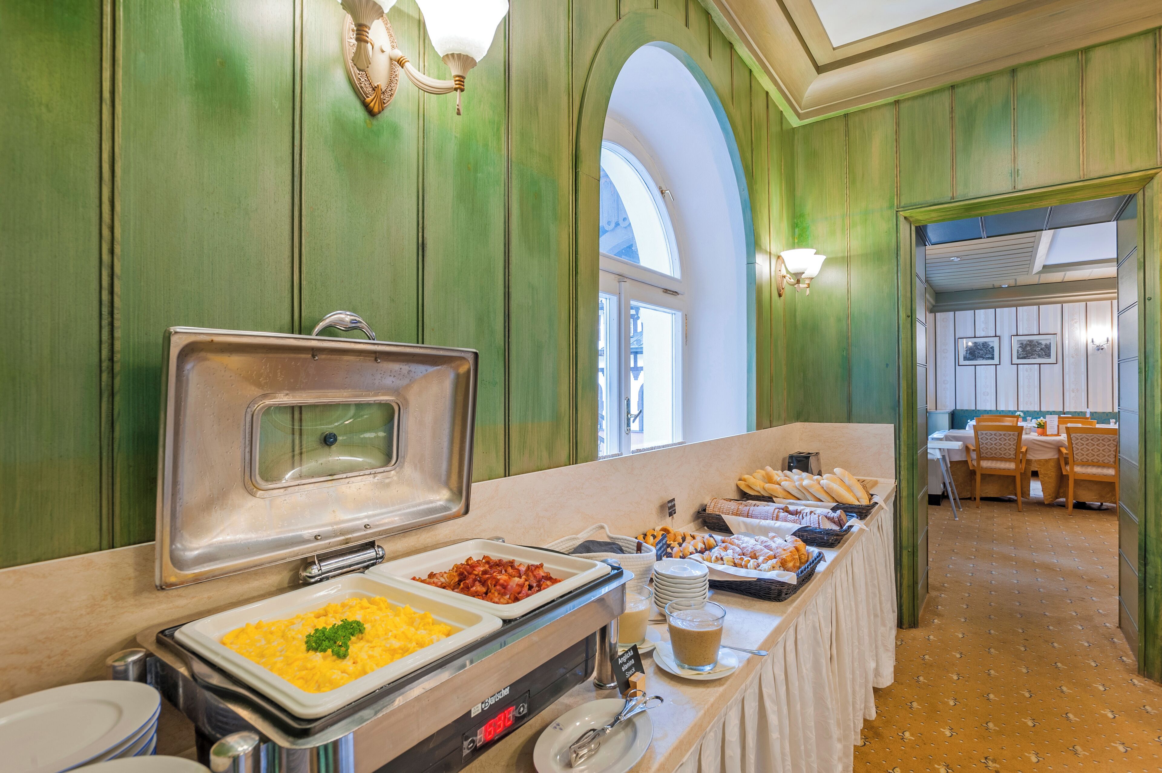 A buffet area with various food options, a coffee station, and a dining area with chairs and tables.
