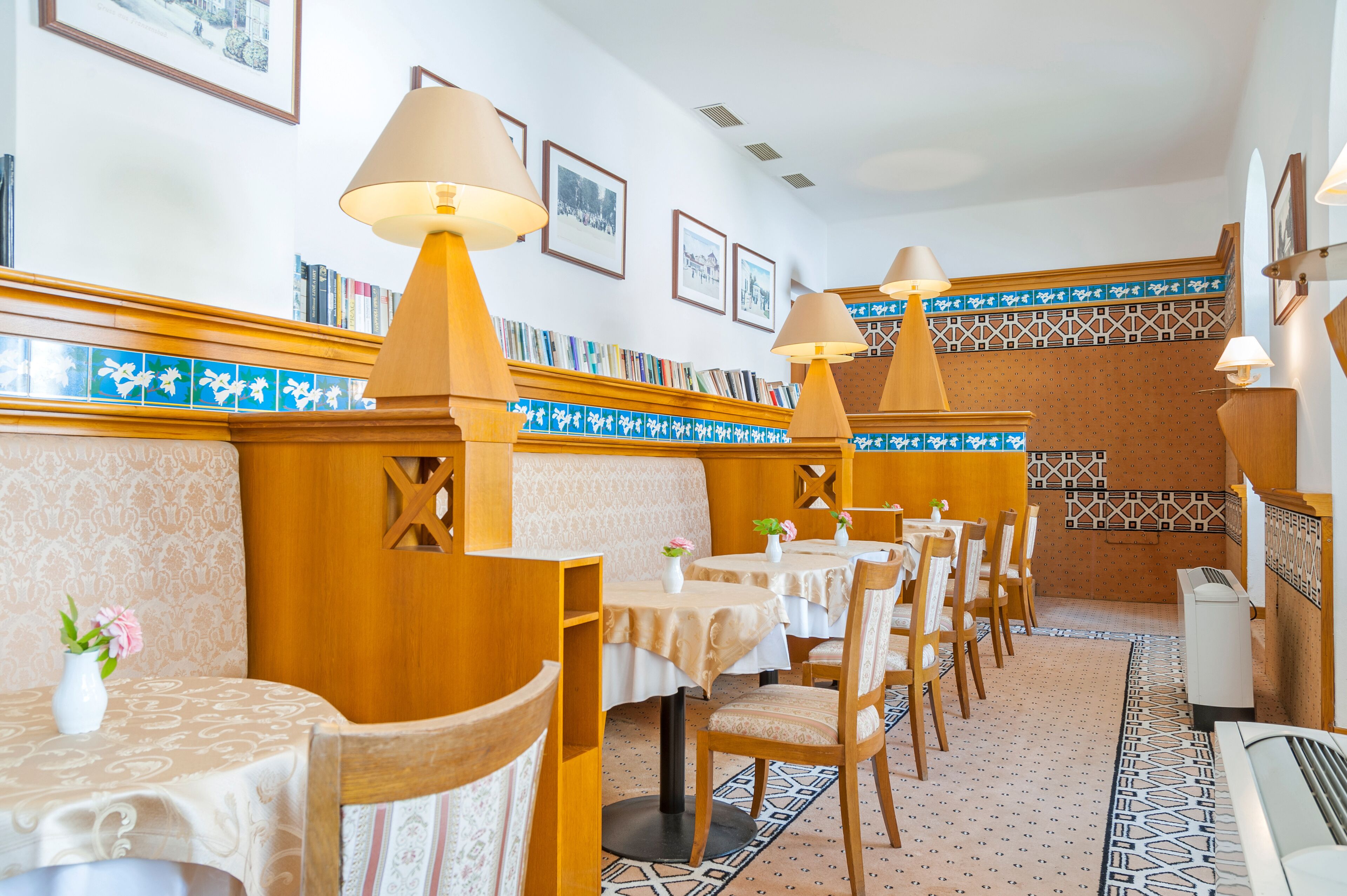 A restaurant with wooden booths, tables with white tablecloths, and patterned tile walls.