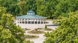 A gazebo with a dome roof surrounded by a landscaped garden with pathways and benches. - Tři Lilie (Frantiskovy Lazne)