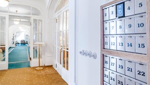 A hotel corridor with a wooden floor, a blue carpet, and a wall with numbered calendar doors. - Tři Lilie (Frantiskovy Lazne)