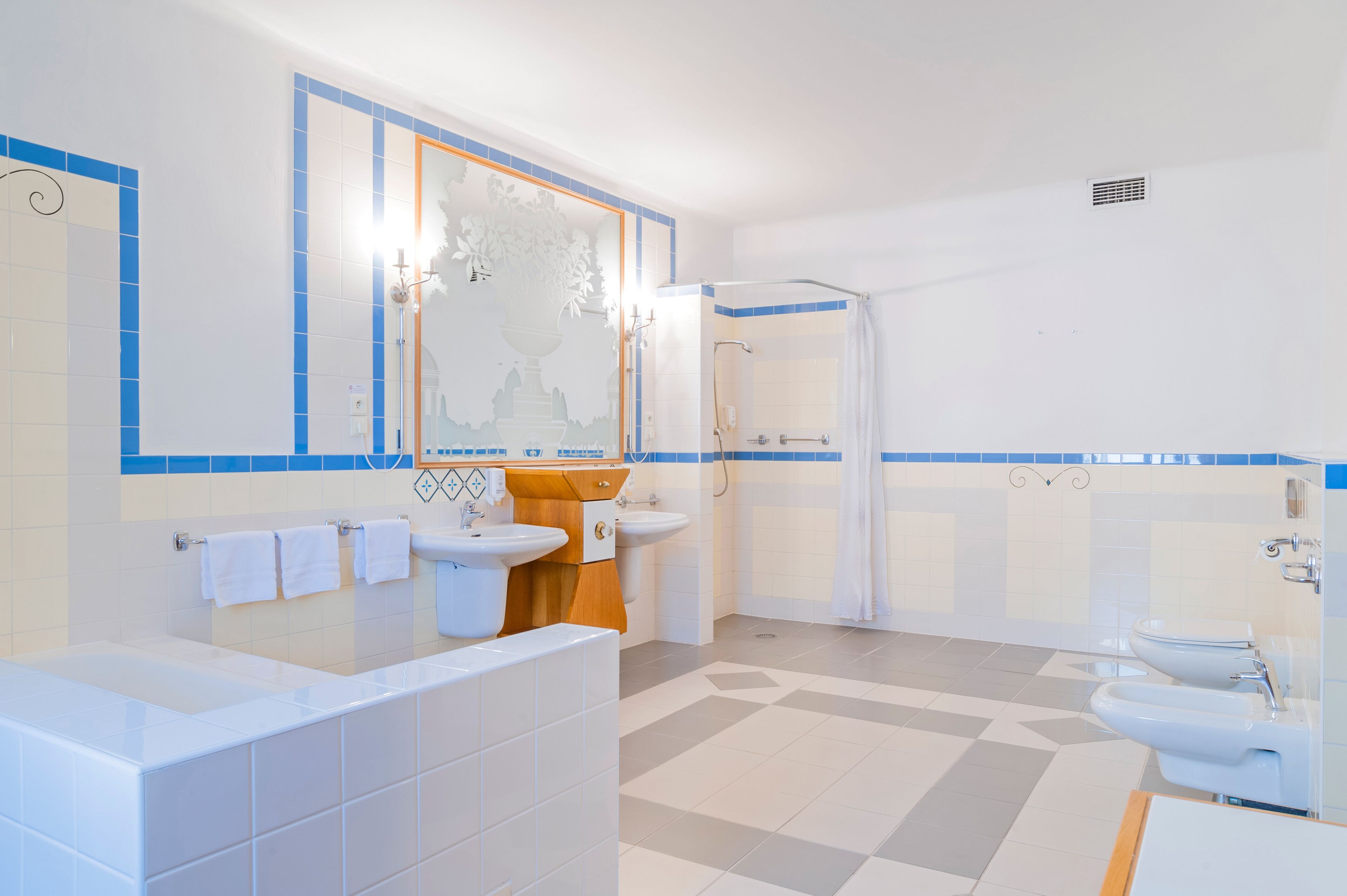 A modern bathroom with a bathtub, two sinks, and a shower area.