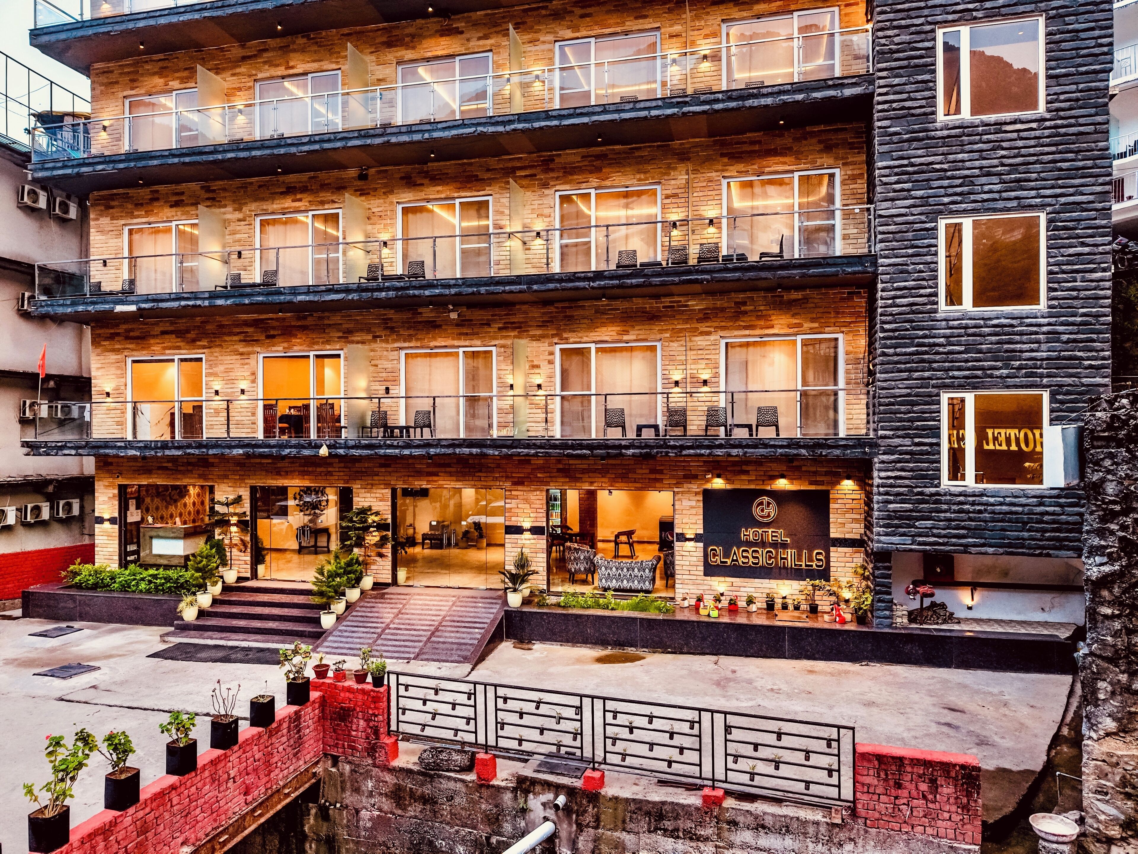 Een meerlaags hotel met een bakstenen gevel, balkons en een zichtbare ingang met een bord waarop 'HOTEL CLASSIC HILLS' staat.