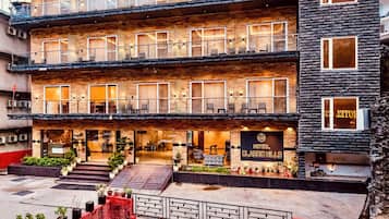 Un hôtel à plusieurs étages, doté d’une façade en briques, de balcons et d’une entrée bien visible, sur laquelle on peut lire l’inscription « HÔTEL CLASSIC HILLS ».