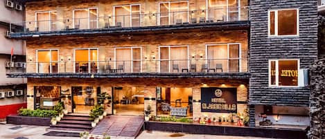 Un hotel de varios pisos con fachada de ladrillo, balcones y una entrada visible con un cartel que dice 'HOTEL CLASSIC HILLS'.
