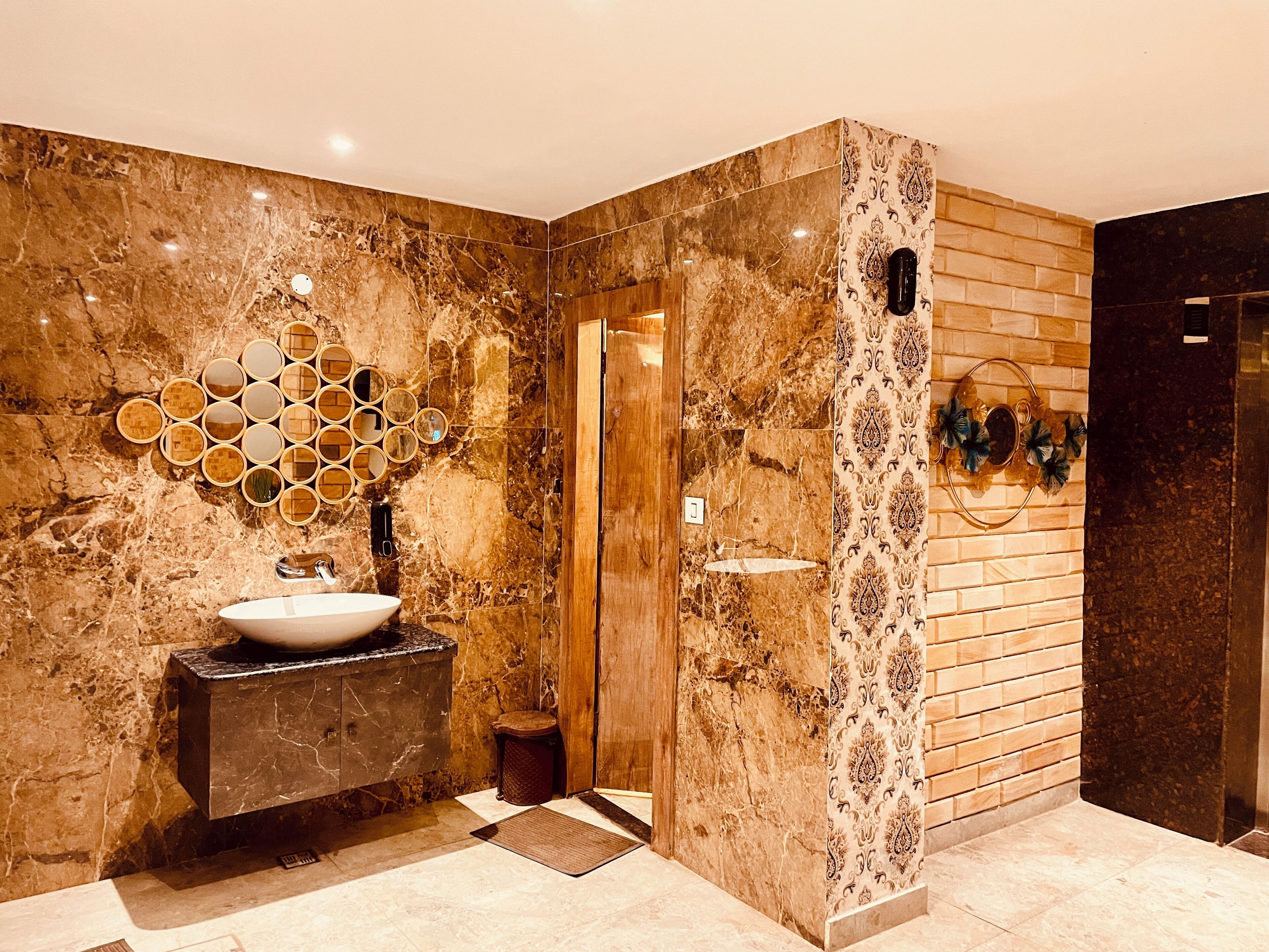 A bathroom with a marble vanity, a sink, and a mirror wall.