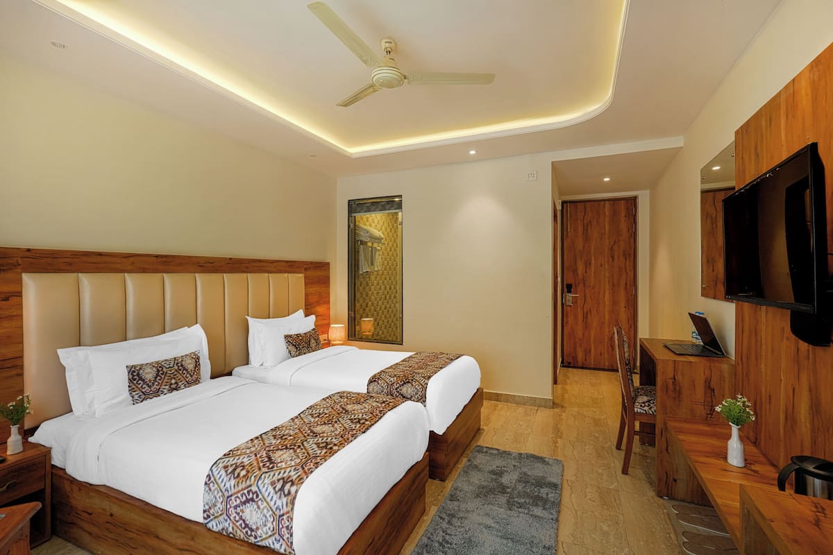 A hotel room with a large bed, a desk, a chair, a TV, and a ceiling fan.