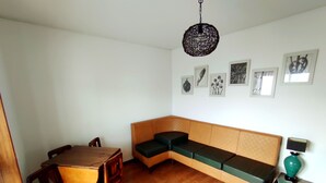 Um quarto com uma mesa de jantar de madeira, um banco, um sofá verde com almofadas e um lustre.