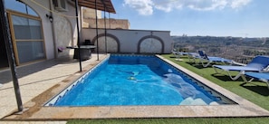 Relax by the pool with a view of the surrounding landscape, surrounded by lounge chairs and a low wall.