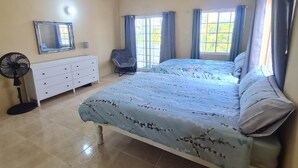 A bedroom with a bed, a dresser, a chair, and a fan. - 3-bed Sea View House in Priory St Ann (St. Ann's Bay)