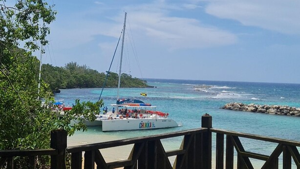 A coastal scene with a sailboat docked near a rocky shoreline, surrounded by lush greenery and clear blue waters. - 3-bed Sea View House in Priory St Ann (St. Ann's Bay)