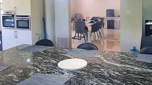 A modern kitchen with a granite countertop, three pendant lights, and a dining area with a table and chairs. - 3-bed Sea View House in Priory St Ann (St. Ann's Bay)