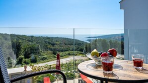 A balcony with a table, a bowl of fruit, and two glasses of red drink. - Villa Rozeta with sea view (Šegotići)