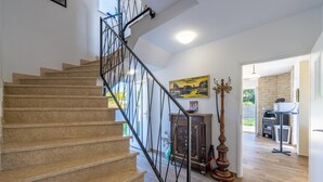 A staircase with a metal railing leading to a room with a wooden floor, a cabinet, and a painting on the wall. - Villa Rozeta with sea view (Šegotići)
