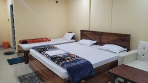 Et hotelværelse med to senge, en loftsvifte, et lille bord og en hvid sofa.