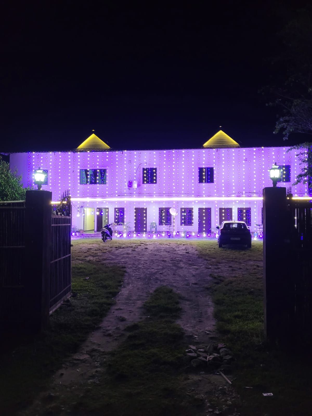 A building with a purple exterior and a yellow roof, featuring a series of windows and a gated entrance.