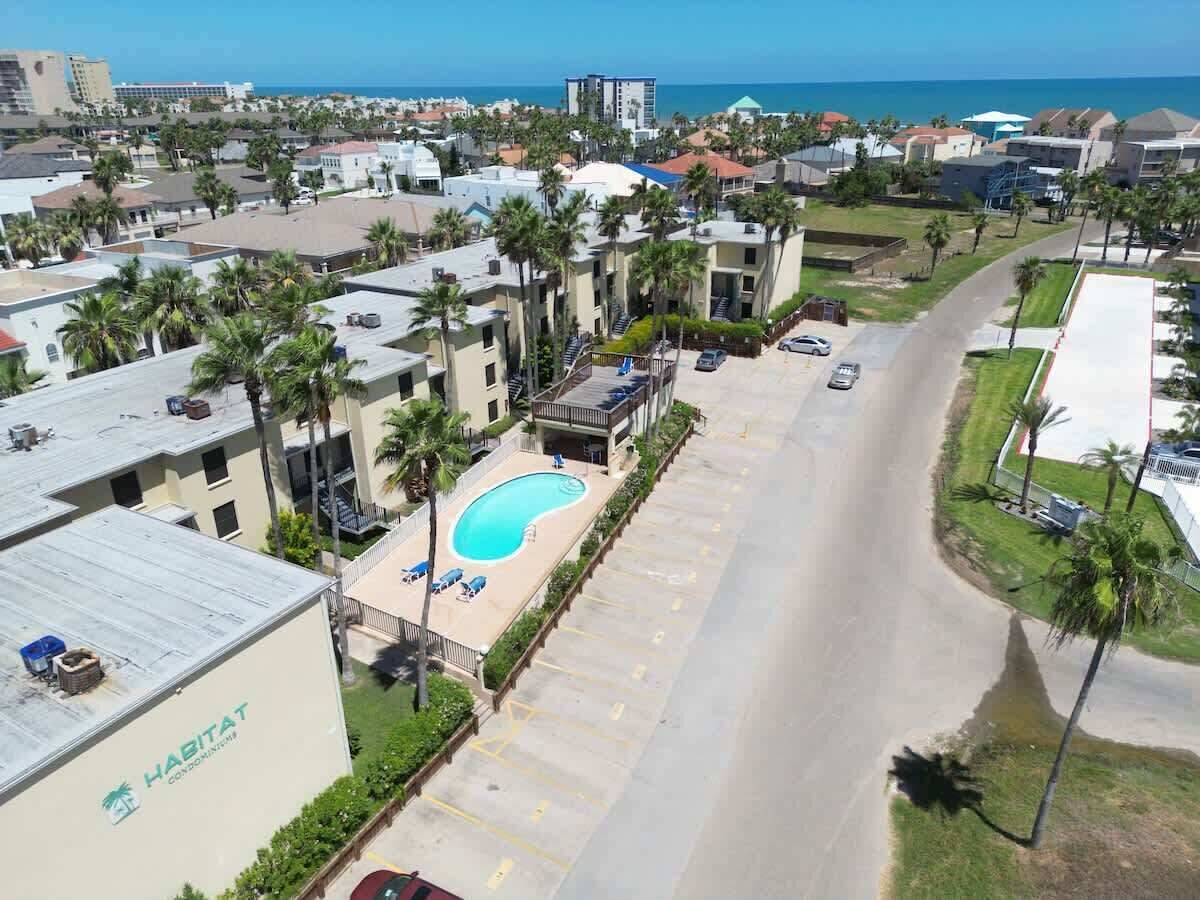 A residential area with a swimming pool, a road, and a view of the ocean.