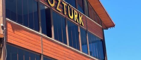 A building with the sign "ÖZTÜRK" on the facade, large windows, and a wooden exterior.