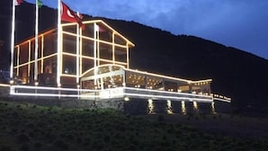 A building with a glass facade, multiple floors, and a balcony area. - Uzungöl Ozturk Hotel  (Çaykara)