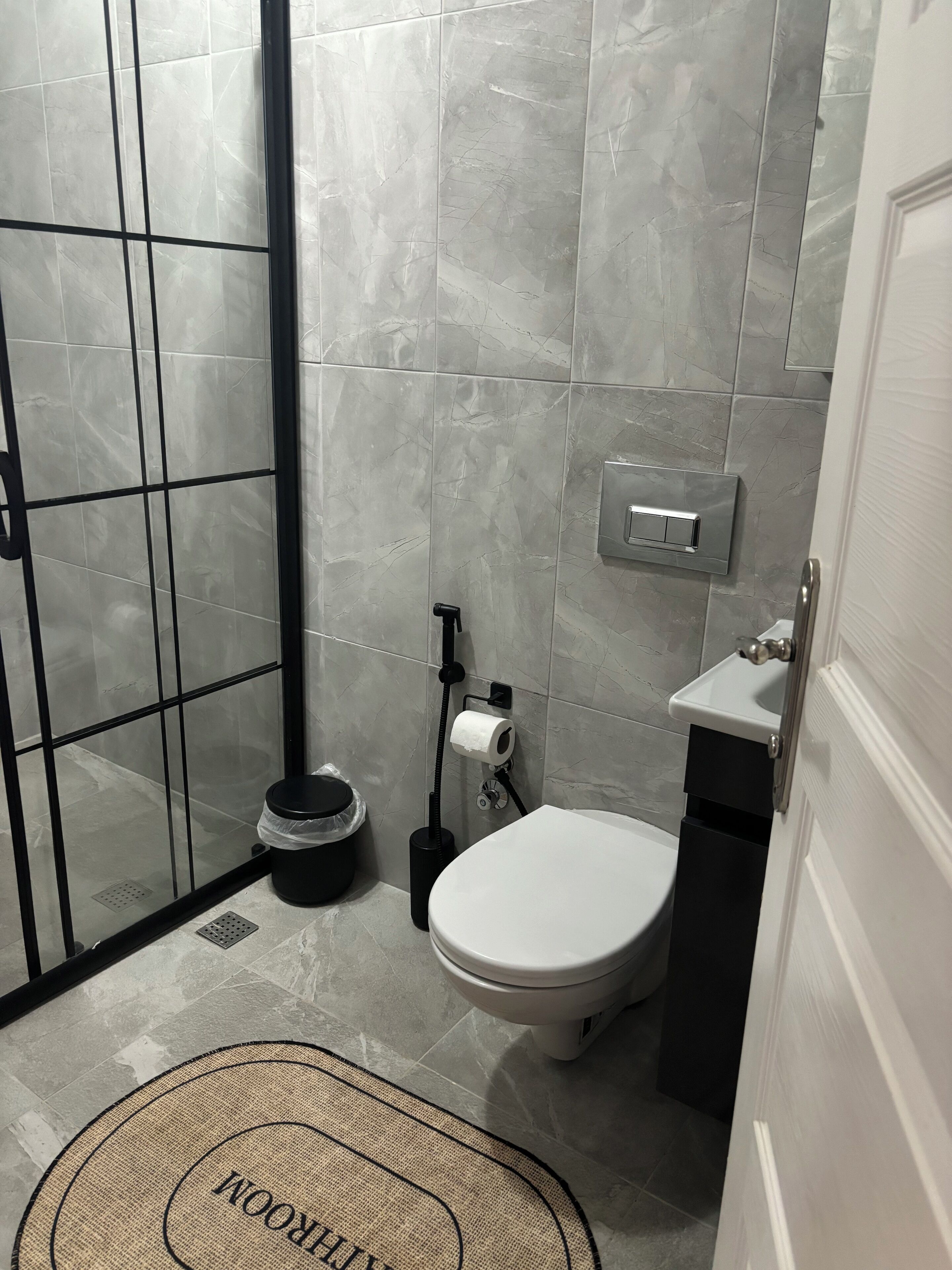 Un baño con inodoro, bidé, dispensador de toallas y zona de ducha con puerta de cristal.