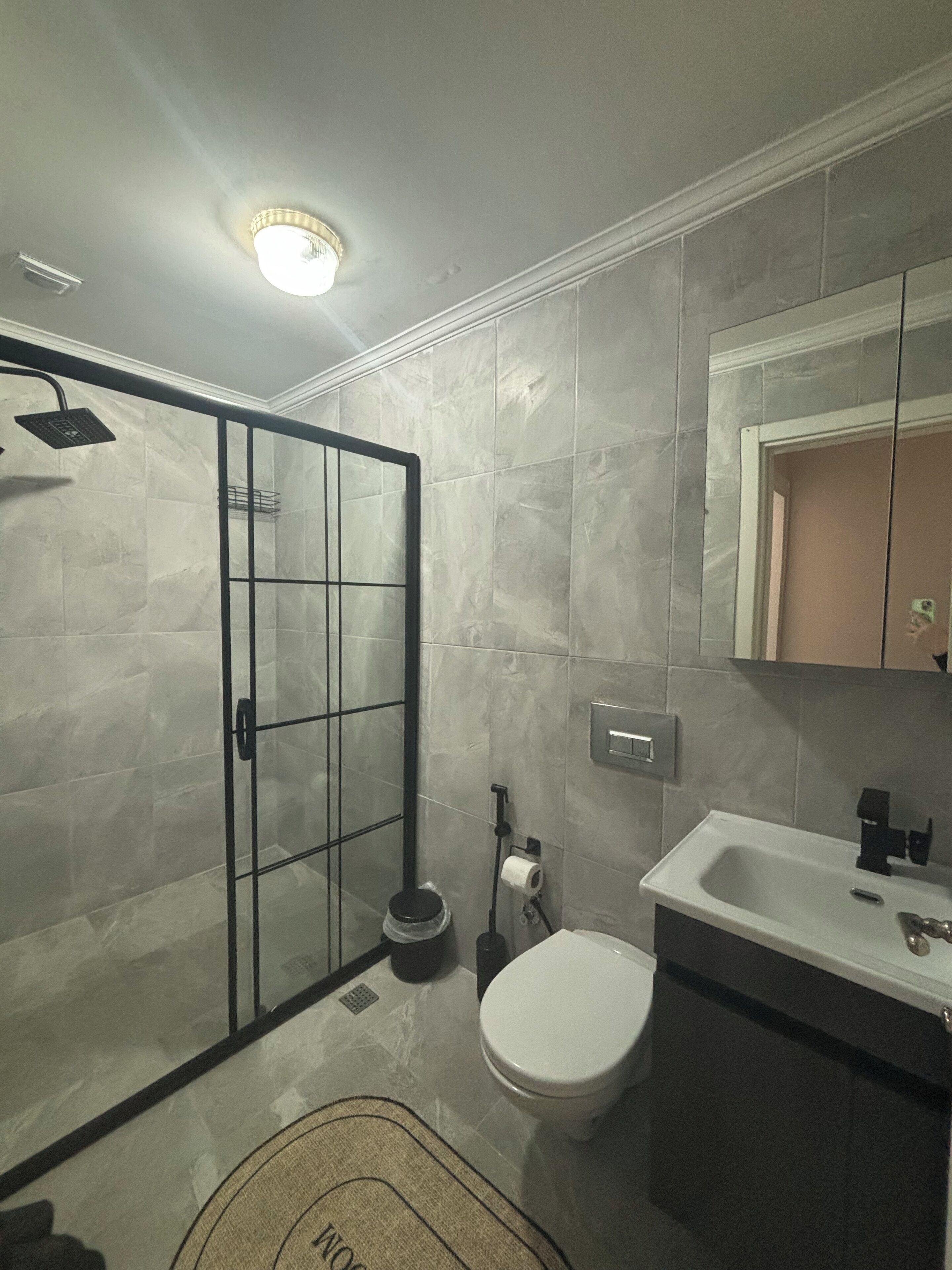 Ein Badezimmer mit Dusche, Toilette, Waschbecken und Spiegel.