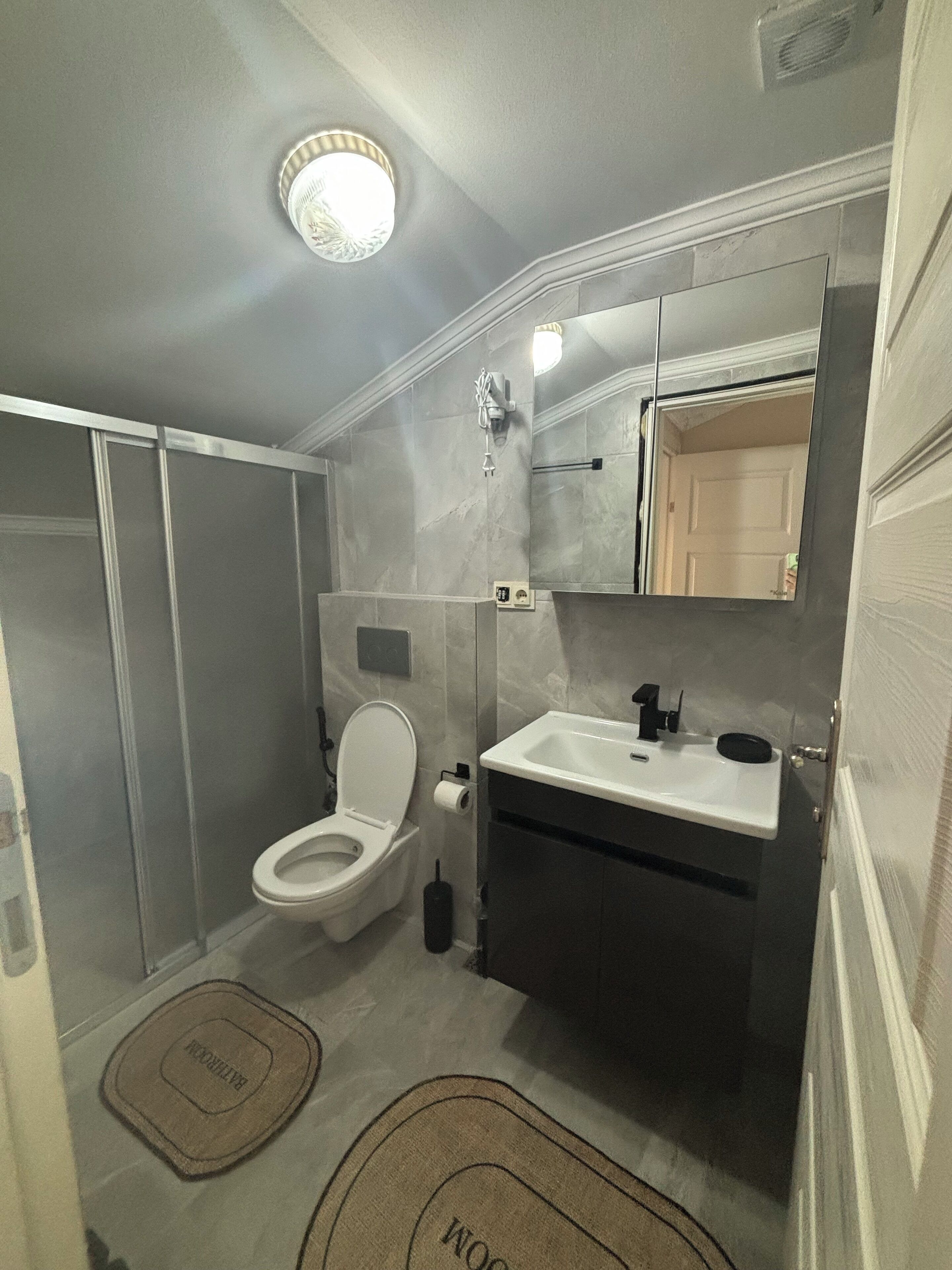 Une petite salle de bain comprenant des toilettes, un lavabo et un miroir.