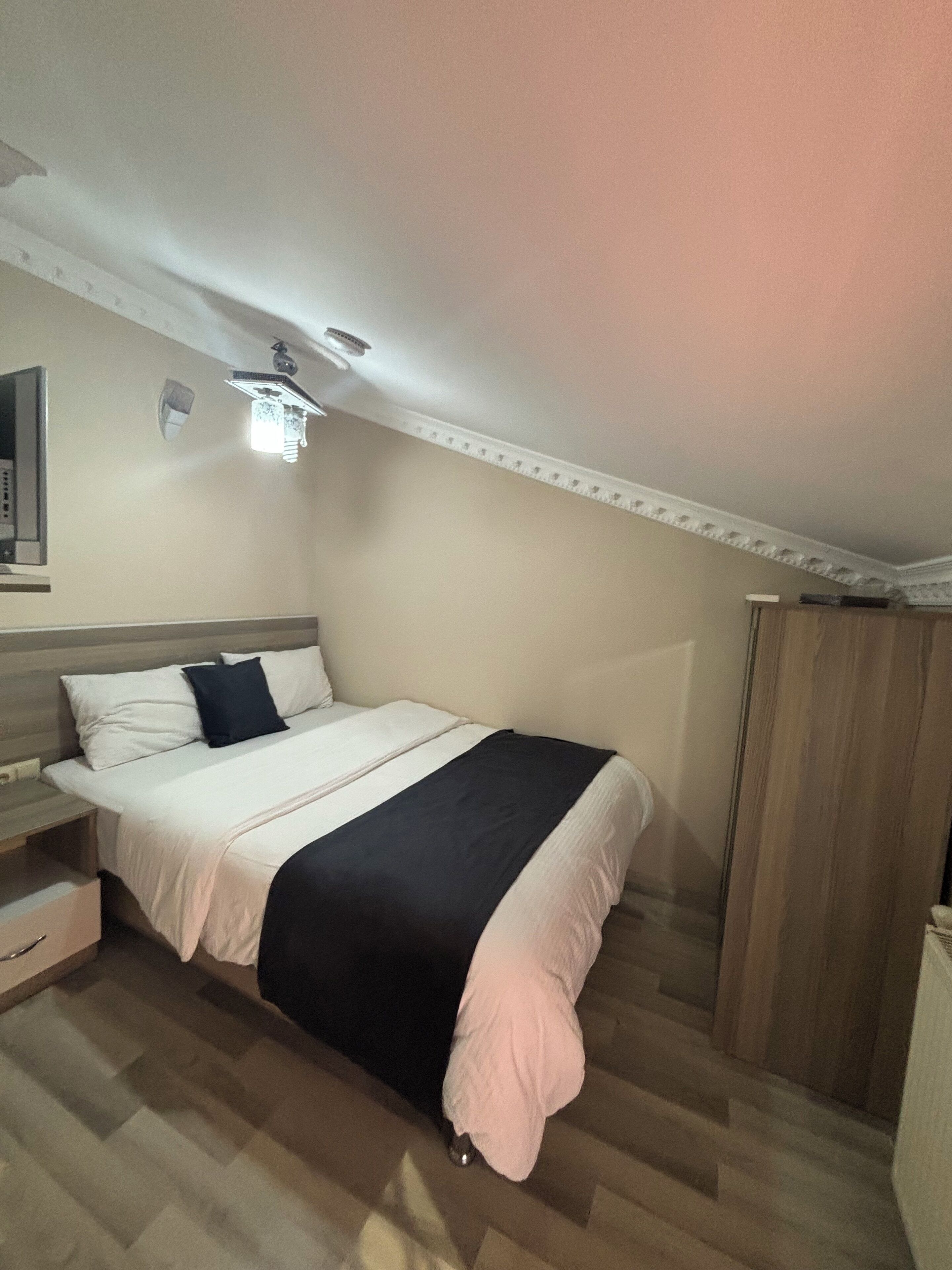 A bedroom with a bed, a nightstand, a wardrobe, and a ceiling fan.
