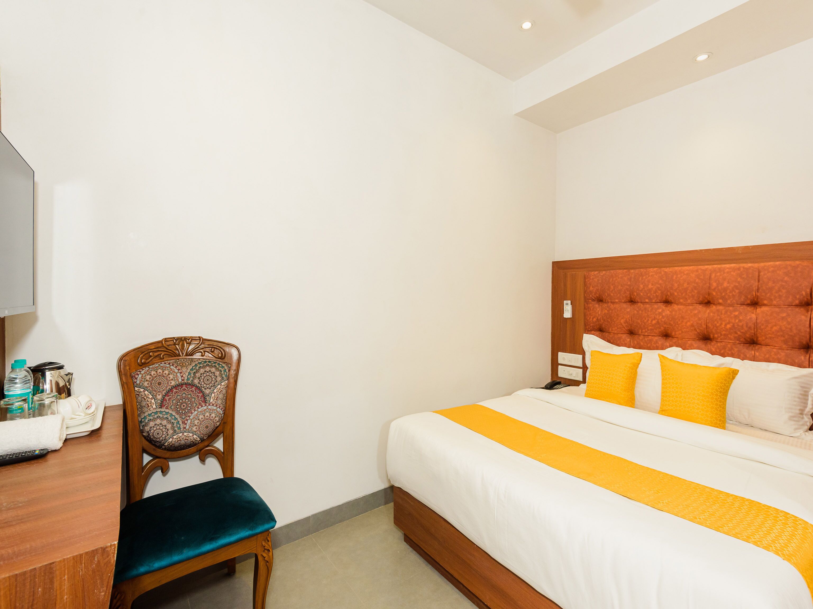 Ein Hotelzimmer mit einem hölzernen Bett, einem Schreibtisch aus Holz und einem Stuhl mit gemustertem Kissen.